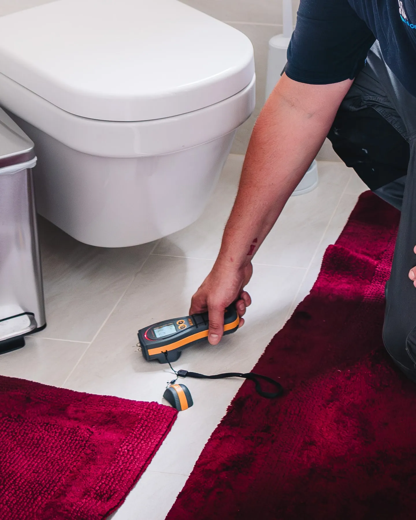 ADI engineer measuring moisture in a bathroom floor beside a toilet